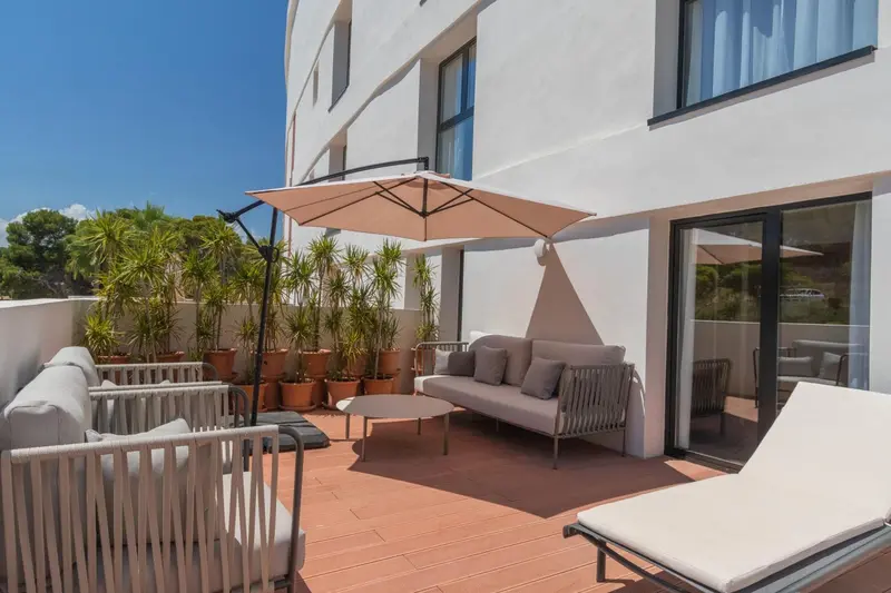 Terrasse aménagée avec canapés, transats et parasol.
