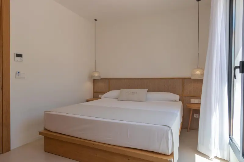 Une chambre lumineuse avec un grand lit et des suspensions décoratives.