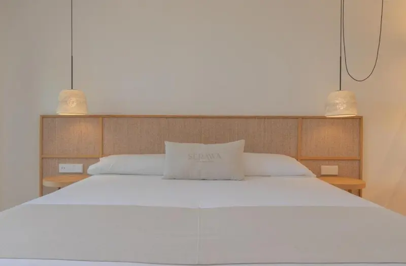Un lit double blanc avec des oreillers dans une chambre lumineuse.