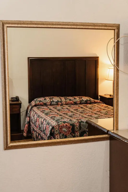 Une chambre avec un lit recouvert d'une courtepointe et un miroir doré.