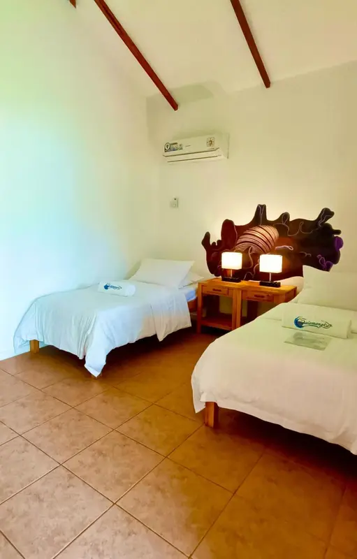 Chambre lumineuse avec deux lits simples et une décoration murale marine.