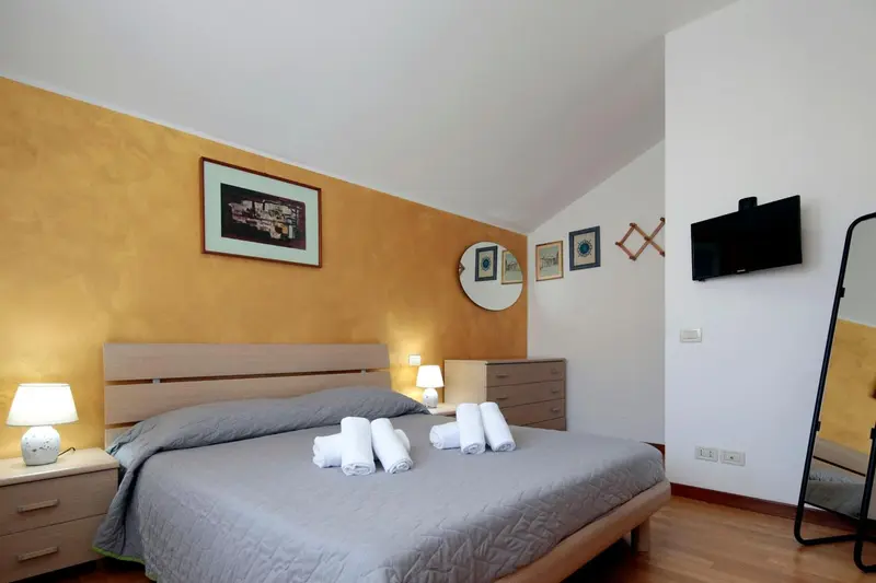 Une chambre lumineuse avec un grand lit et des tableaux décoratifs au mur.