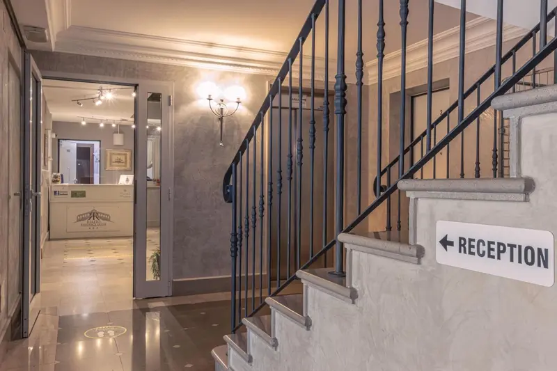 Un couloir d'hôtel mène à un comptoir d'accueil éclairé par des appliques murales.