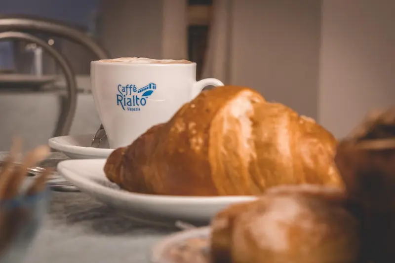 Une tasse de café et un croissant sur une assiette.