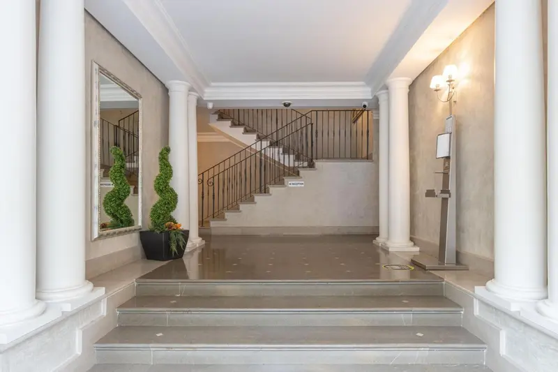 Un hall d'entrée lumineux avec un escalier et des colonnes.