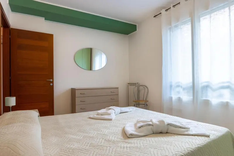 Une chambre lumineuse avec un lit recouvert d'une courtepointe blanche et de serviettes.