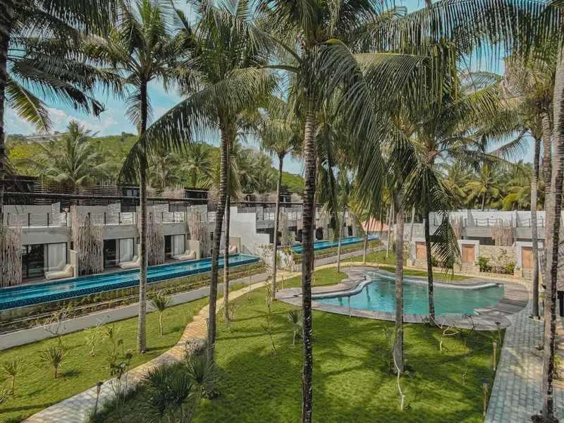 Vue aérienne d'un complexe hôtelier tropical avec des piscines et une végétation luxuriante.