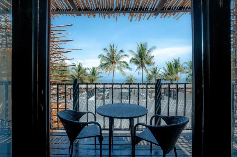 Terrasse avec mobilier de jardin donnant sur une plage de cocotiers.