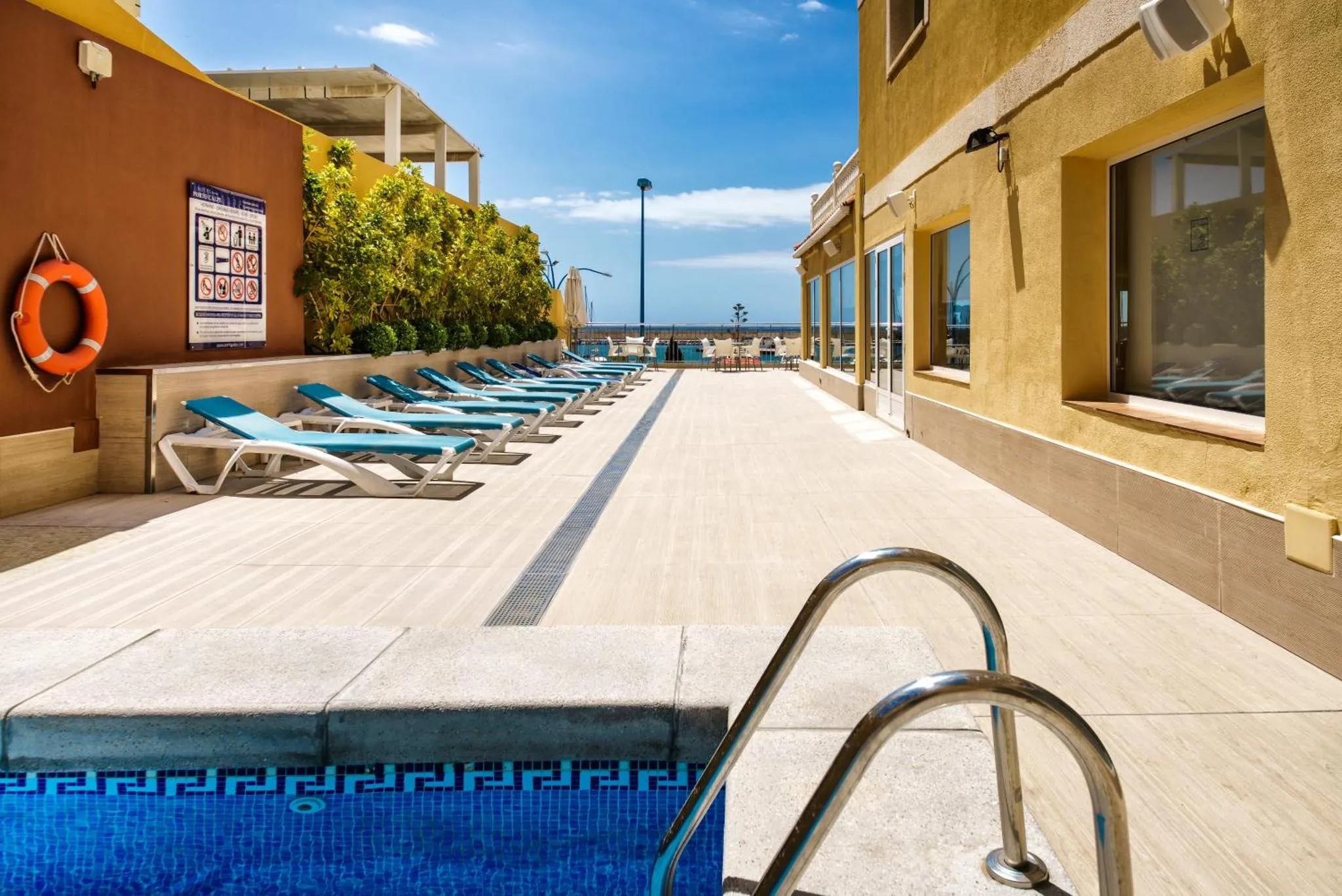 Terrasse avec transats et piscine en bord de mer.