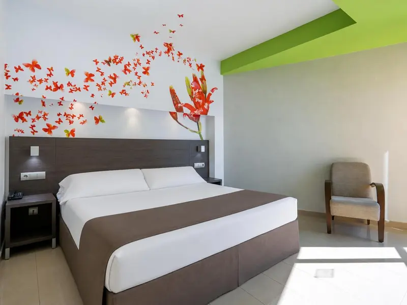 Une chambre lumineuse avec un grand lit et un fauteuil.