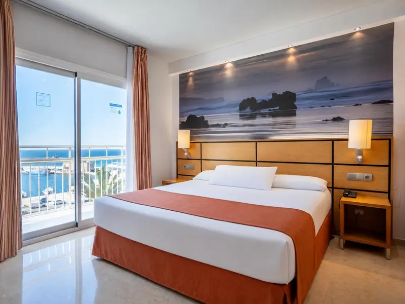 Chambre lumineuse avec un grand lit et vue sur la mer.