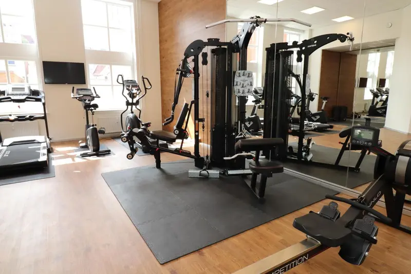 Une salle de sport lumineuse avec divers équipements de musculation et cardiovasculaire.