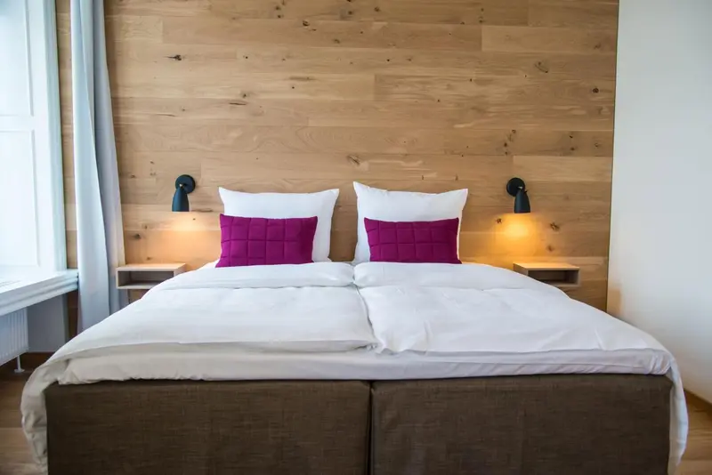Un lit double avec une tête de lit en bois et des oreillers violets.