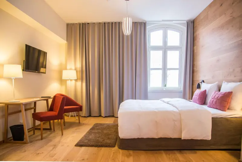 Une chambre lumineuse avec un lit, un bureau et un fauteuil.