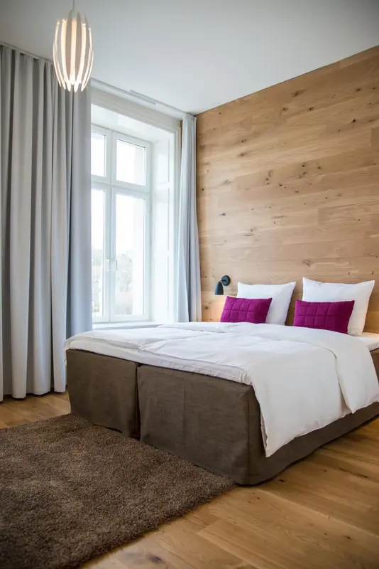 Une chambre lumineuse avec un grand lit et un mur en bois.