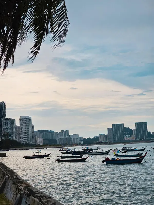 Des bateaux de pêche longent une côte urbaine au crépuscule.