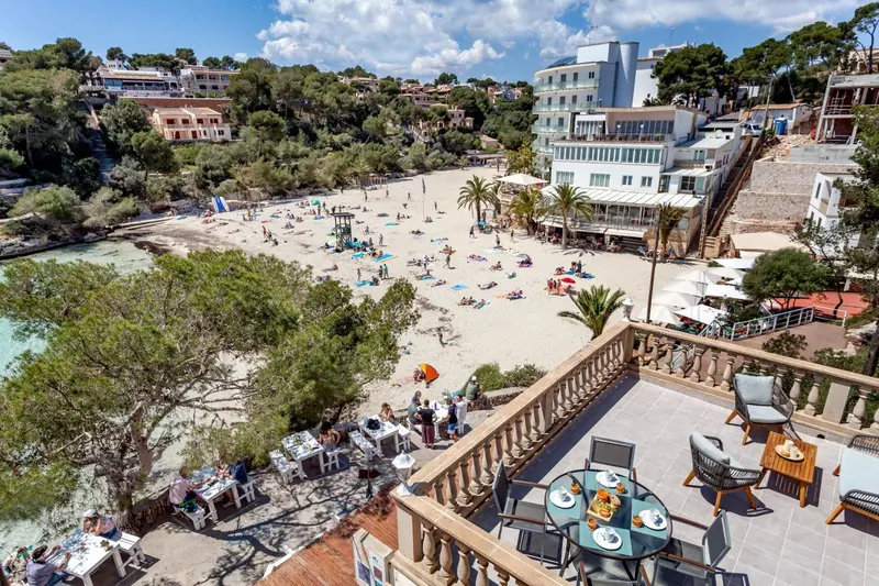 Vue aérienne d'une plage ensoleillée avec des transats et un restaurant en terrasse.