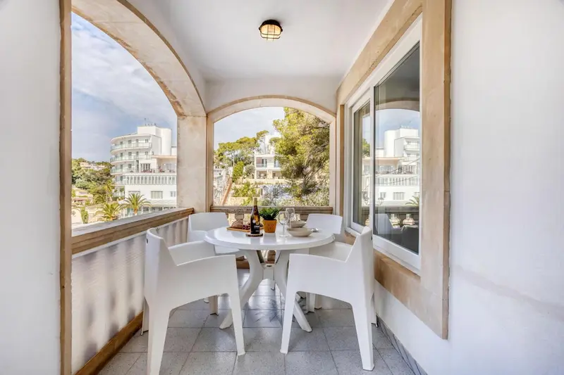 Une table ronde et des chaises blanches sur une terrasse avec vue sur la mer.