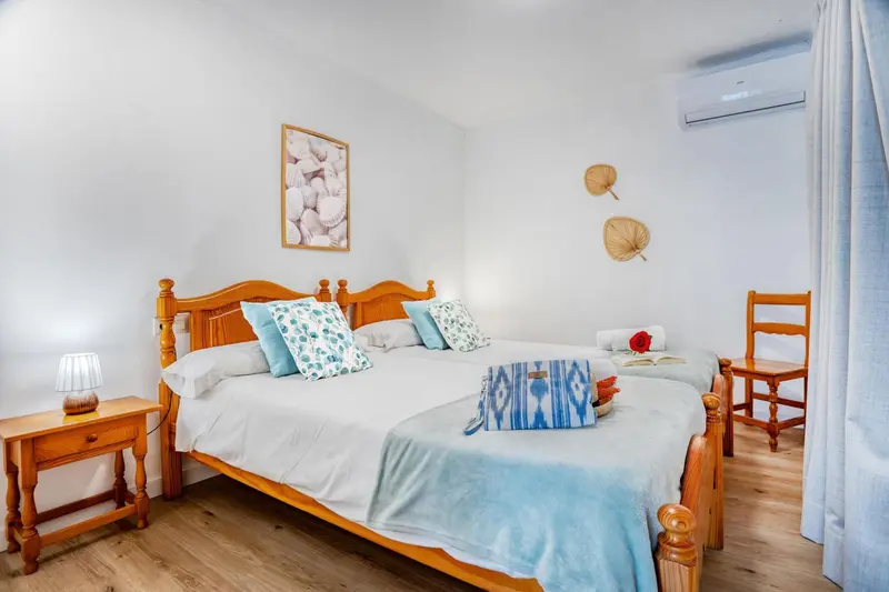 Une chambre lumineuse avec un grand lit recouvert d'une courtepointe et de coussins.