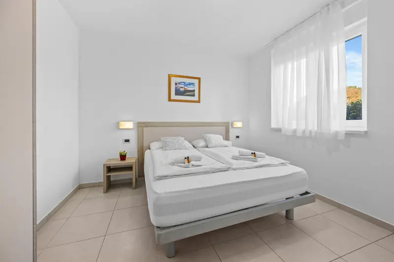 Chambre lumineuse avec un grand lit et une fenêtre.