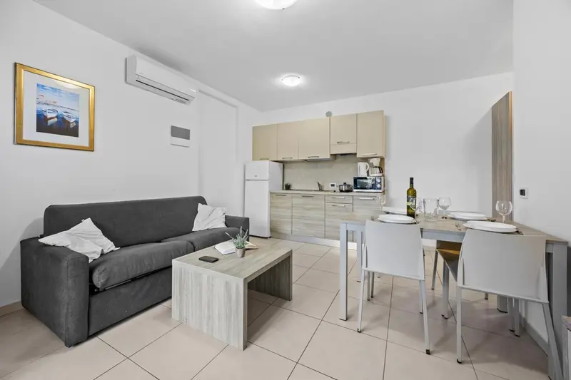 Espace de vie lumineux avec canapé, table basse et cuisine équipée.