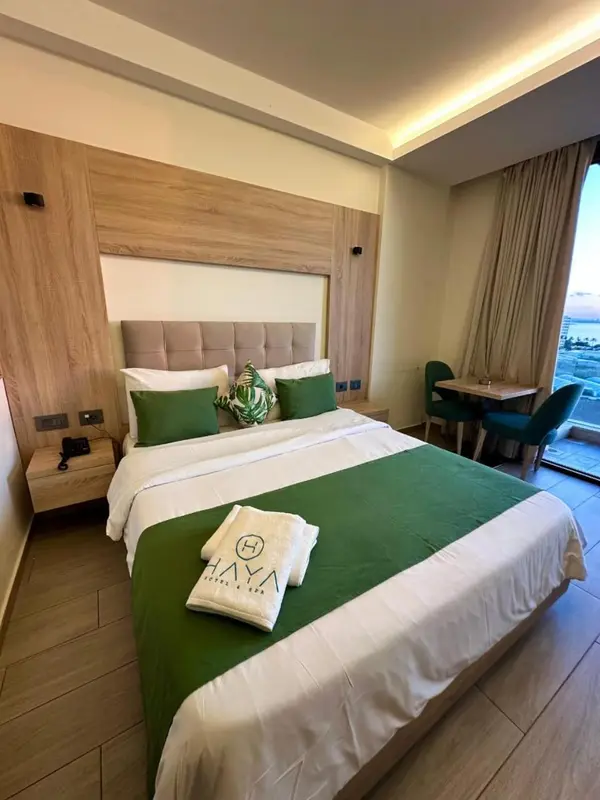Une chambre d'hôtel moderne avec un grand lit recouvert d'une couette verte et de coussins.