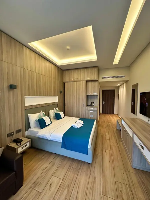 Chambre lumineuse avec un grand lit et un parquet clair.