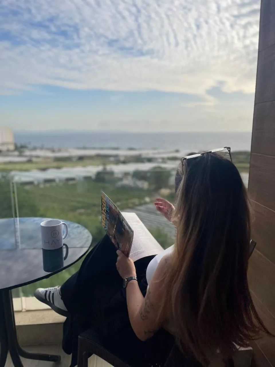 Une personne est assise à une table sur une terrasse avec une vue sur la mer.