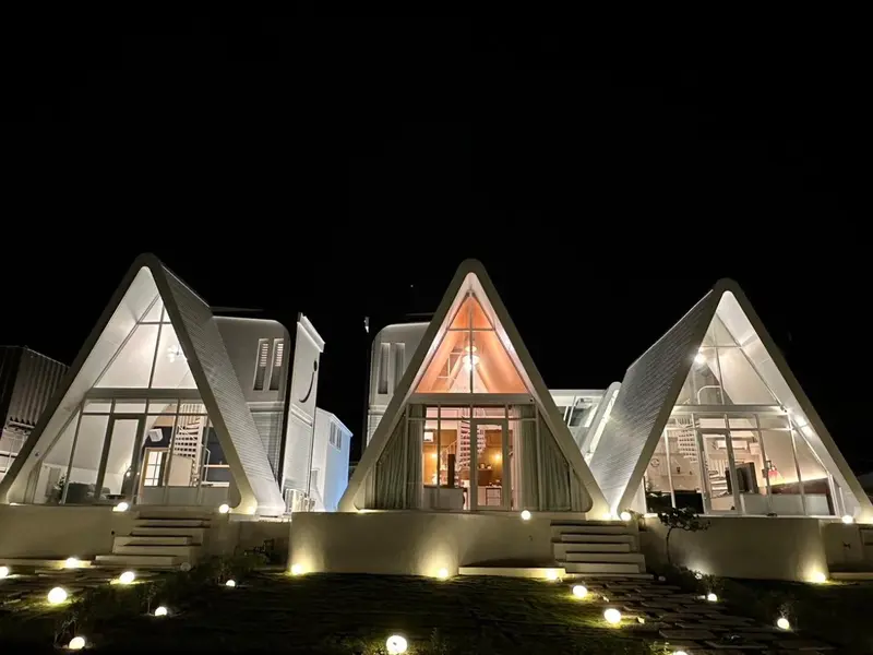 Bâtiments blancs aux formes triangulaires éclairés la nuit.