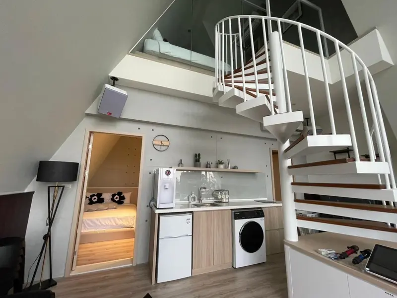 Une cuisine moderne s'ouvre sur un espace de vie avec un escalier en colimaçon.