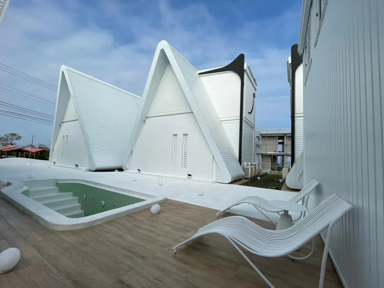 Terrasse blanche avec piscine et mobilier d'extérieur.