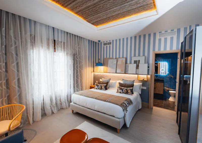 Une chambre lumineuse avec un grand lit et un coin salon.
