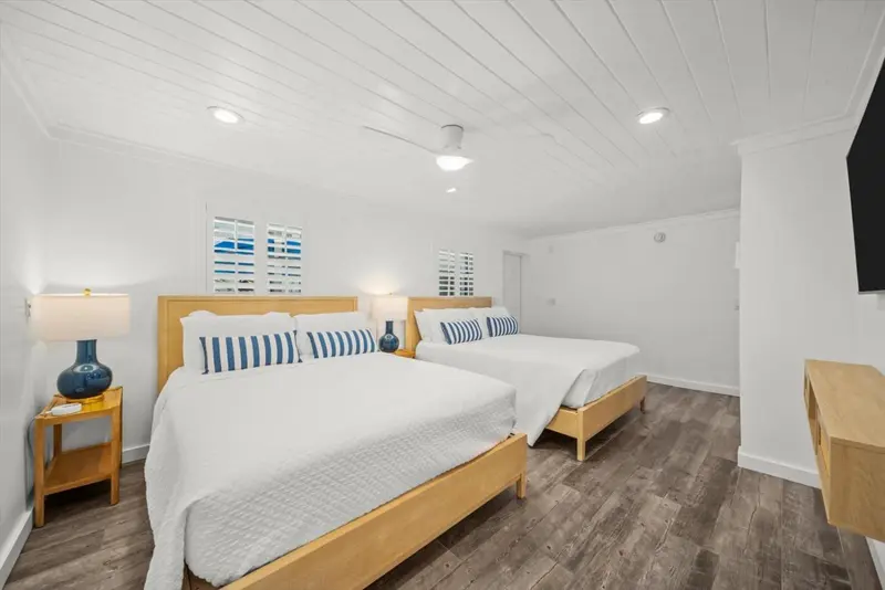 Une chambre lumineuse avec deux lits simples et un ventilateur au plafond.