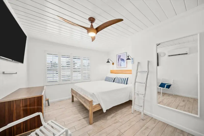 Chambre lumineuse avec un lit double et un ventilateur au plafond.