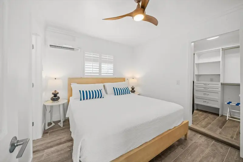 Une chambre lumineuse avec un grand lit recouvert d'une courtepointe blanche et bleue.