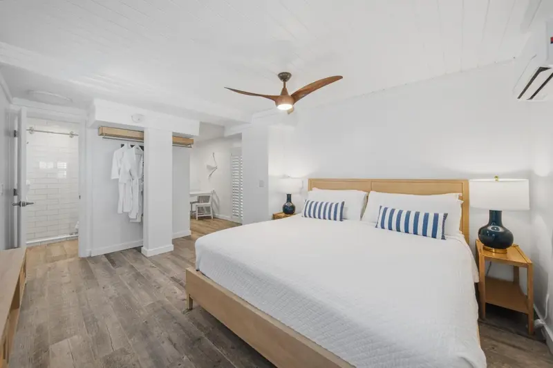 Une chambre lumineuse avec un grand lit et un ventilateur de plafond.