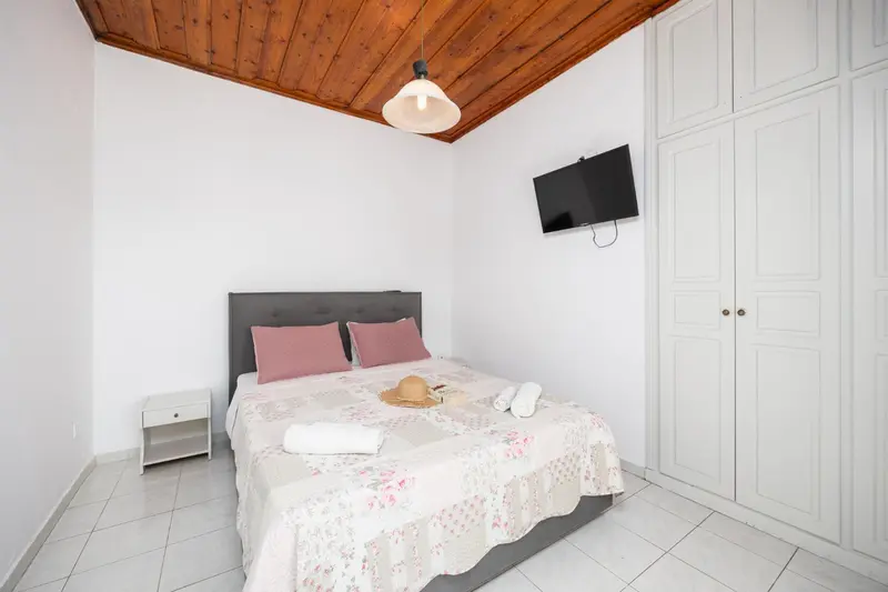 Une chambre lumineuse avec un lit recouvert d'une courtepointe florale et un téléviseur mural.