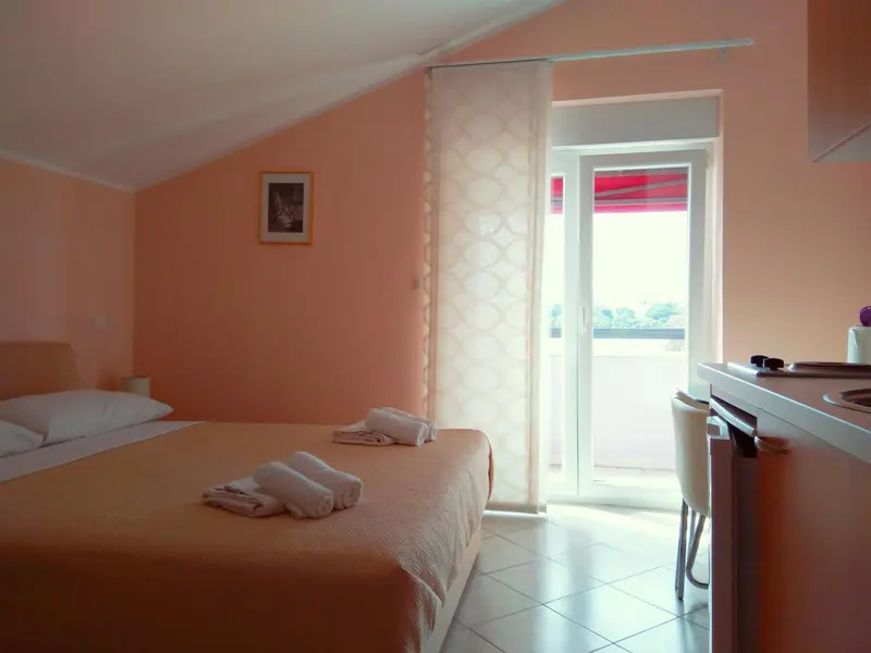 Une chambre lumineuse avec un lit fait et un coin cuisine.