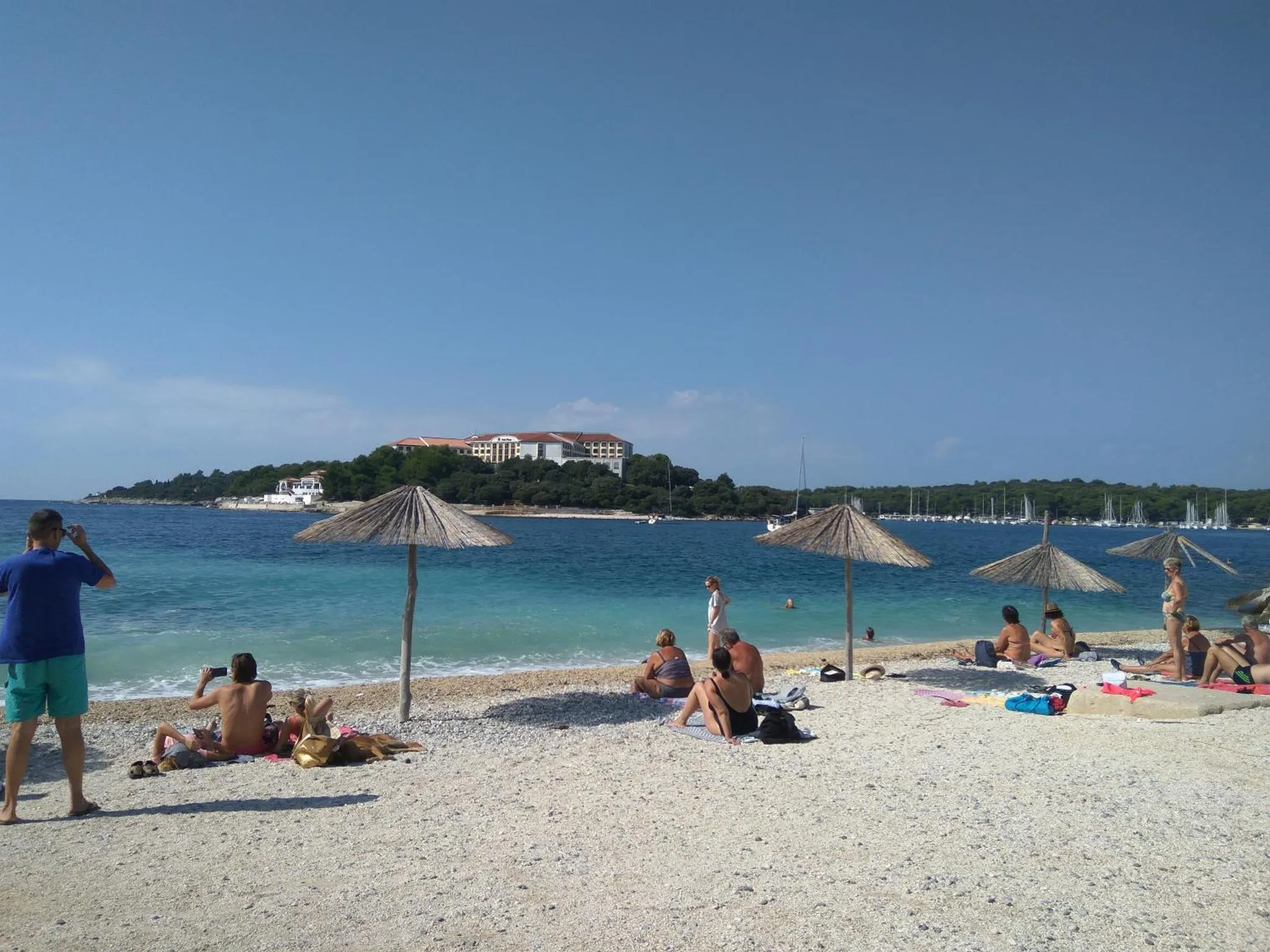 Une plage de sable blanc avec des parasols et des personnes se relaxant au soleil.