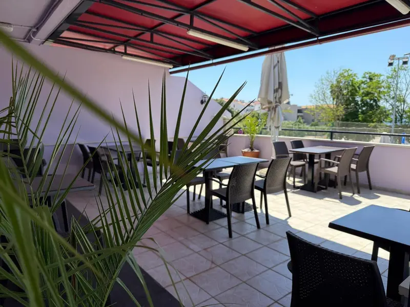 Terrasse ombragée avec tables et chaises pour se restaurer.