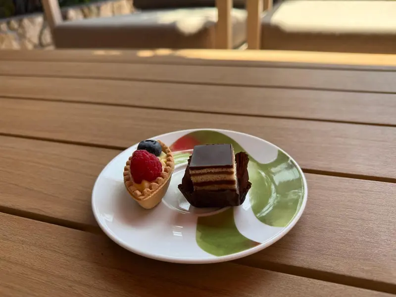 Assiette de desserts avec une tartelette aux fruits rouges et un morceau de gâteau au chocolat.