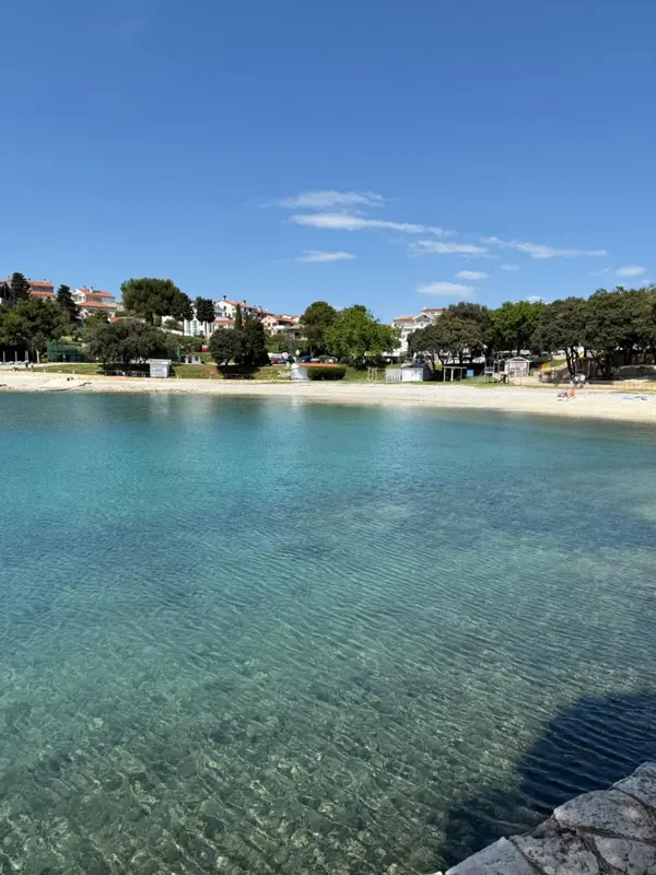 Une plage de sable fin bordée d'une eau turquoise sous un ciel bleu dégagé.