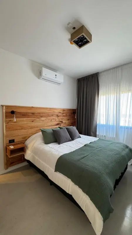 Une chambre lumineuse avec un grand lit recouvert d'une couette verte.