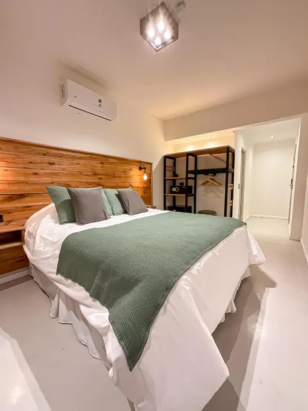 Une chambre lumineuse avec un grand lit recouvert d'une couverture verte.