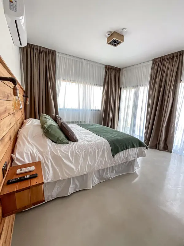 Une chambre lumineuse avec un grand lit recouvert d'une courtepointe blanche et verte.
