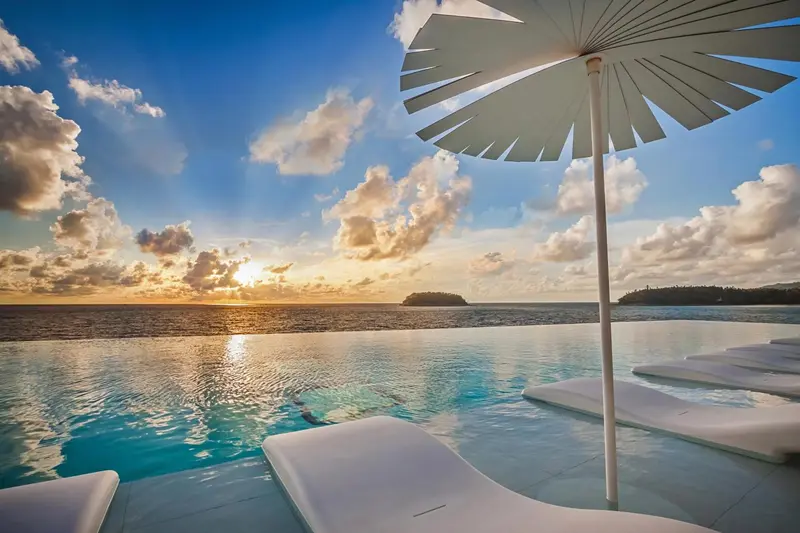 Une piscine à débordement offre une vue sur la mer et le coucher de soleil.