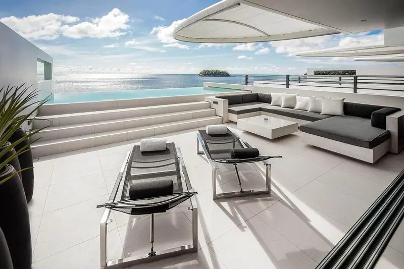 Terrasse moderne avec salon et piscine à débordement donnant sur la mer.