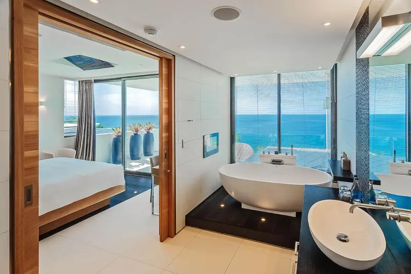 Une salle de bain lumineuse avec une baignoire et une vue sur la mer.