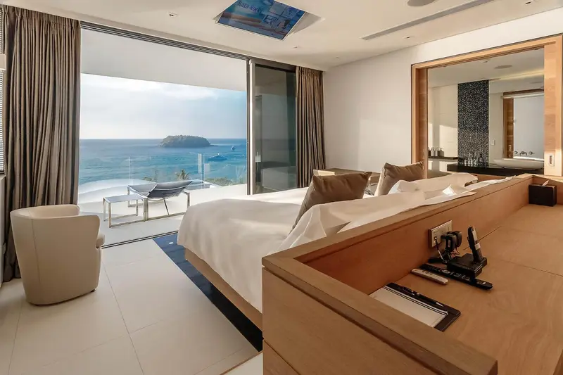 Une chambre lumineuse avec un grand lit donnant sur une vue mer.