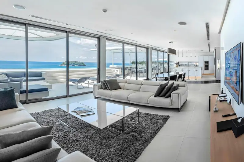 Vaste espace de vie lumineux avec canapés, table basse et vue sur la mer.